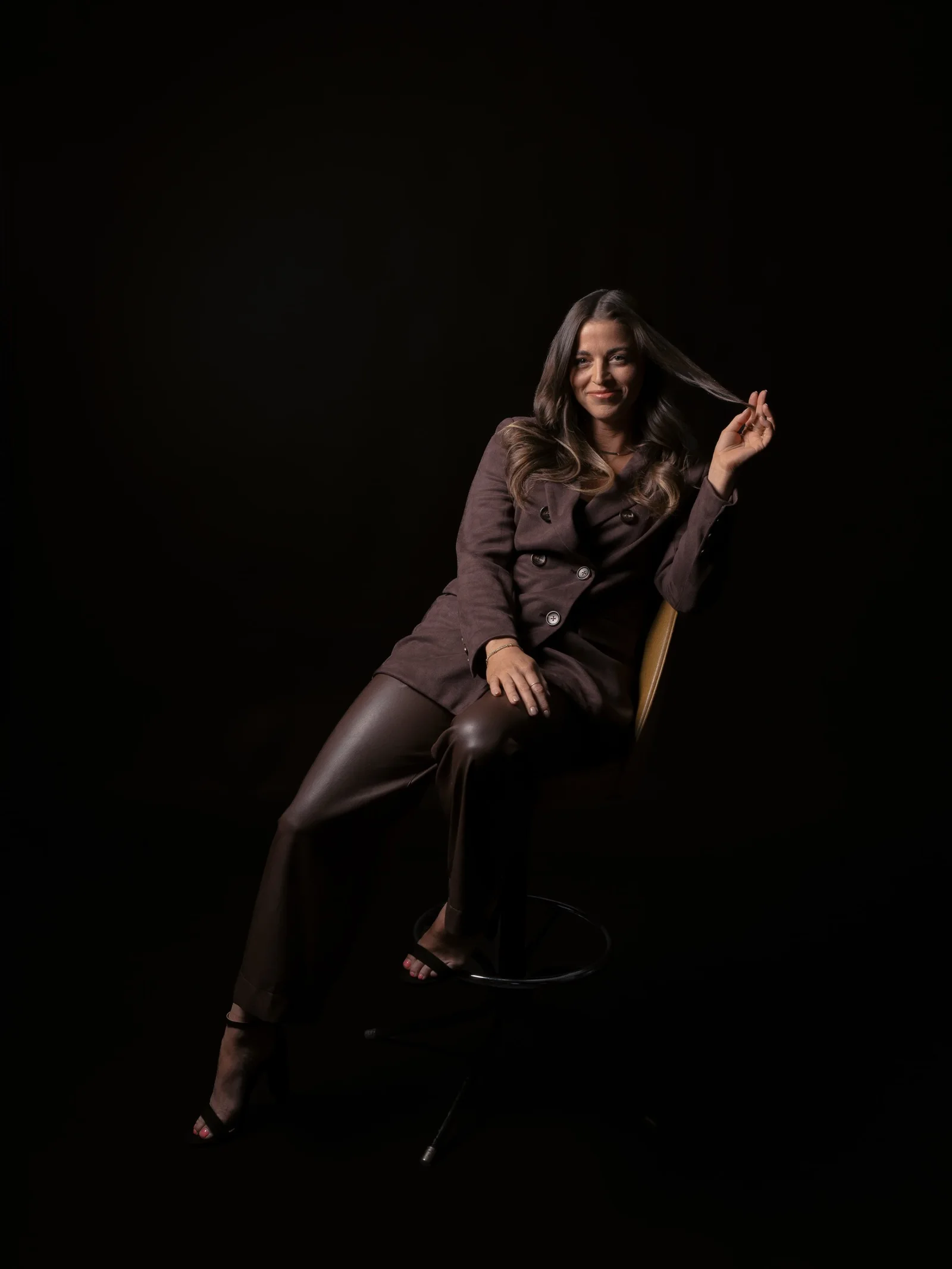 A seated studio portrait against a dark background